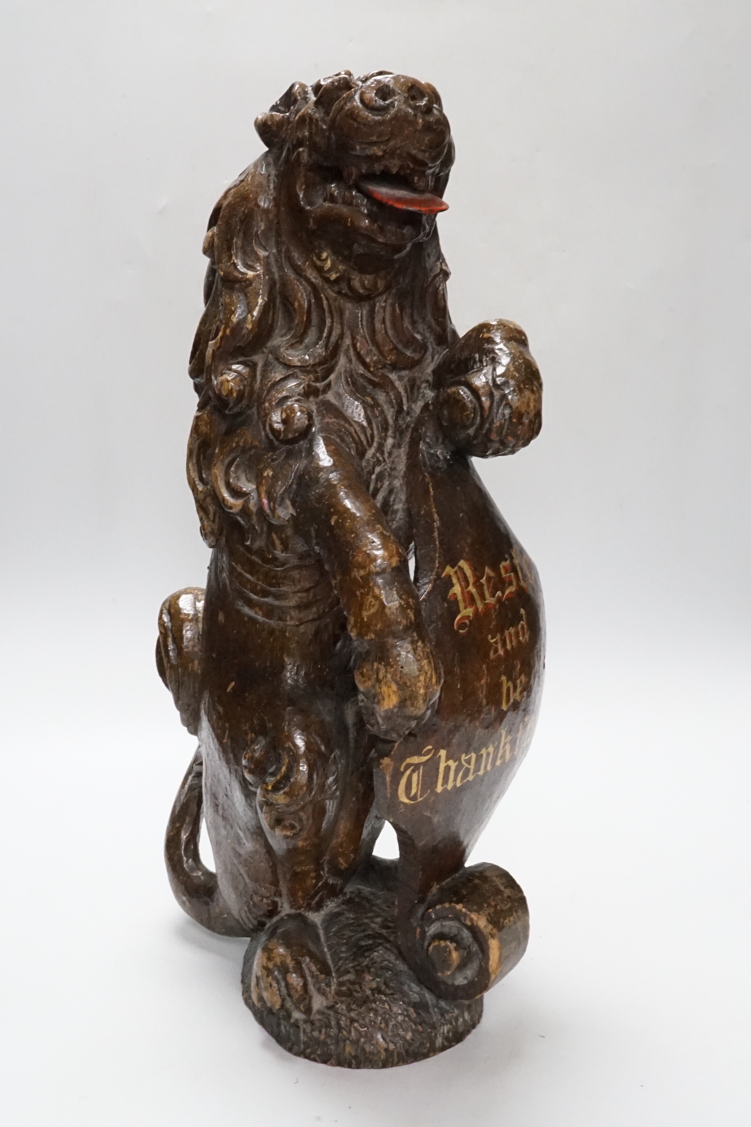 A carved oak lion holding a shield with inscription, possibly 17th/18th century with Victorian inscription Reste and be Thankfall, 48cm high